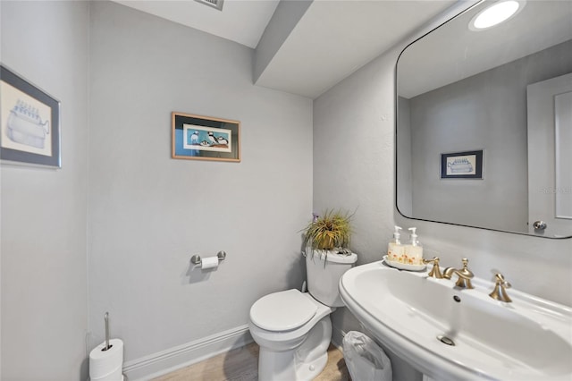 bathroom featuring toilet, wood-type flooring, and sink