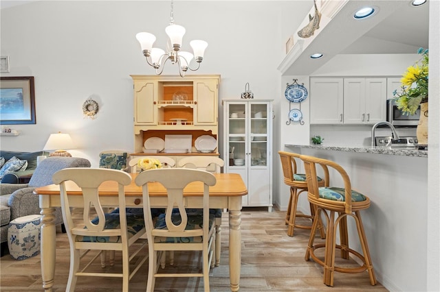 dining room with an inviting chandelier, vaulted ceiling, and light wood-type flooring