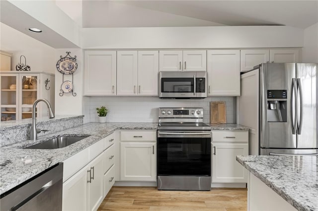 kitchen featuring white cabinetry, lofted ceiling, sink, and appliances with stainless steel finishes