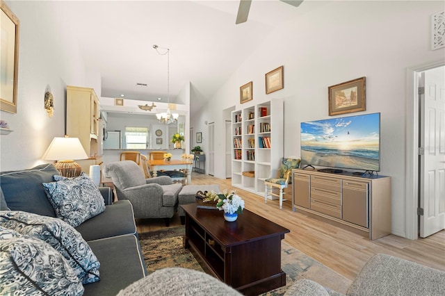 living room featuring light hardwood / wood-style flooring, high vaulted ceiling, and ceiling fan with notable chandelier