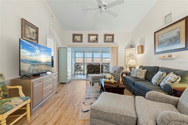 living room with ceiling fan, vaulted ceiling, and light wood-type flooring