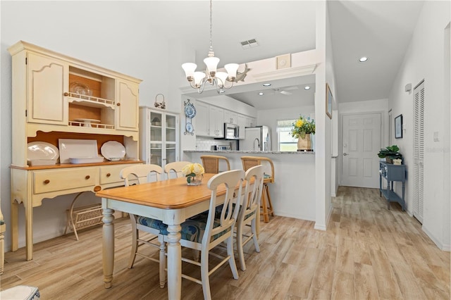 dining room with vaulted ceiling, an inviting chandelier, and light hardwood / wood-style flooring