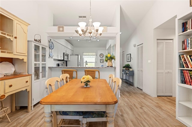 dining room with high vaulted ceiling, a chandelier, and light wood-type flooring