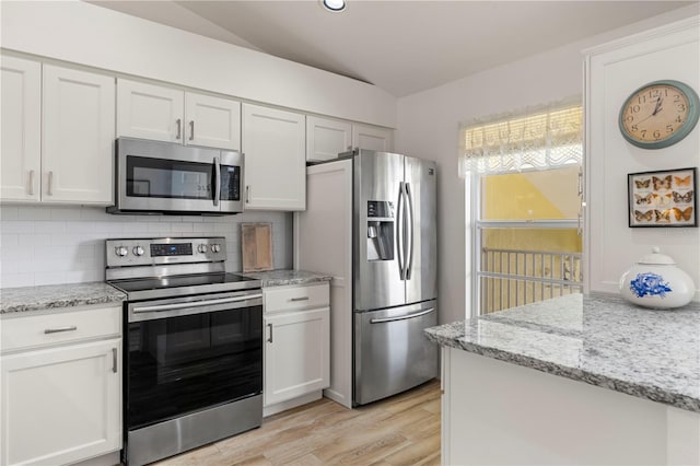 kitchen with white cabinetry, light stone countertops, light hardwood / wood-style flooring, lofted ceiling, and appliances with stainless steel finishes