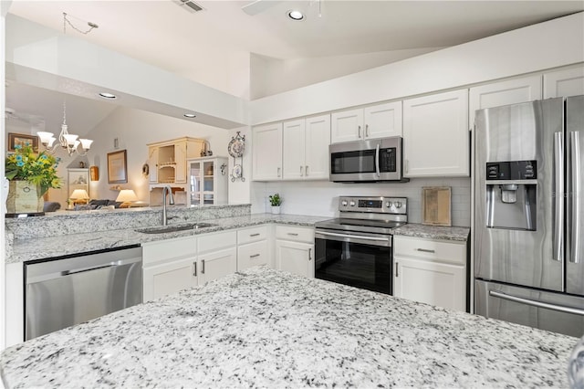 kitchen with sink, stainless steel appliances, a chandelier, vaulted ceiling, and white cabinets