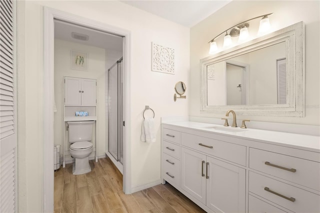 bathroom featuring hardwood / wood-style floors, vanity, a shower with door, and toilet