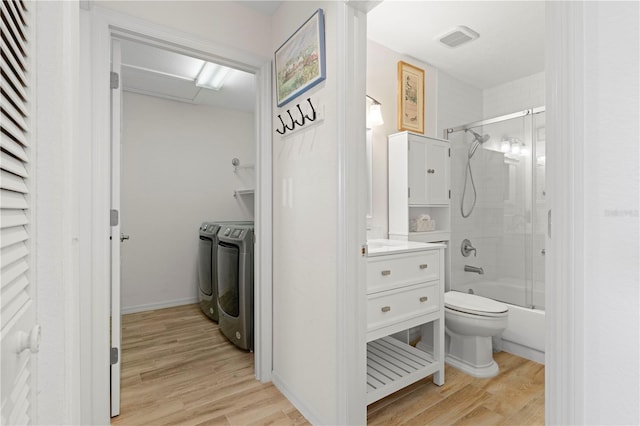 full bathroom featuring shower / bath combination with glass door, independent washer and dryer, hardwood / wood-style flooring, and toilet