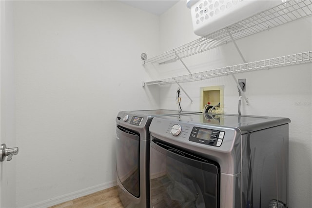 clothes washing area featuring washing machine and dryer and light wood-type flooring