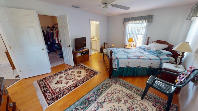 bedroom with ensuite bathroom, a closet, ceiling fan, and light wood-type flooring