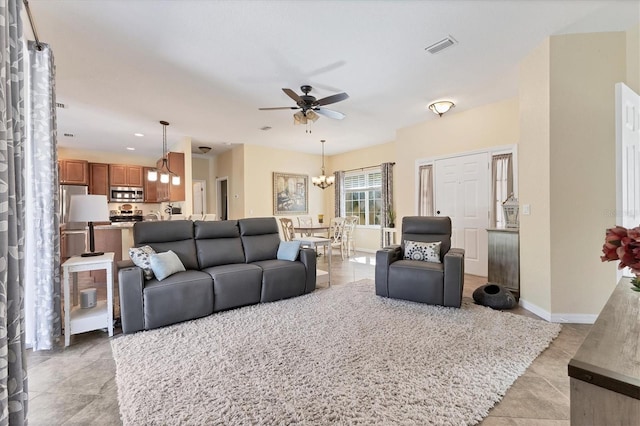 tiled living room featuring ceiling fan with notable chandelier