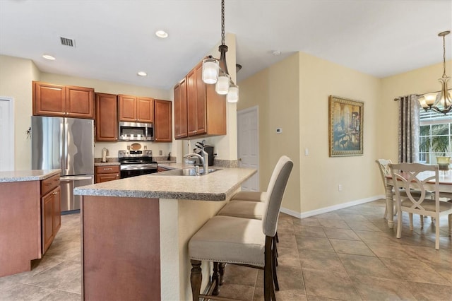 kitchen with kitchen peninsula, sink, decorative light fixtures, and appliances with stainless steel finishes