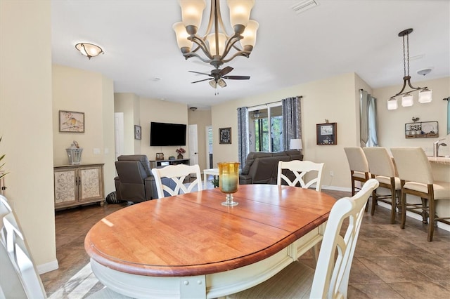 dining area featuring ceiling fan with notable chandelier and dark tile patterned floors