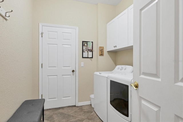 clothes washing area featuring washer and clothes dryer, light tile patterned flooring, and cabinets