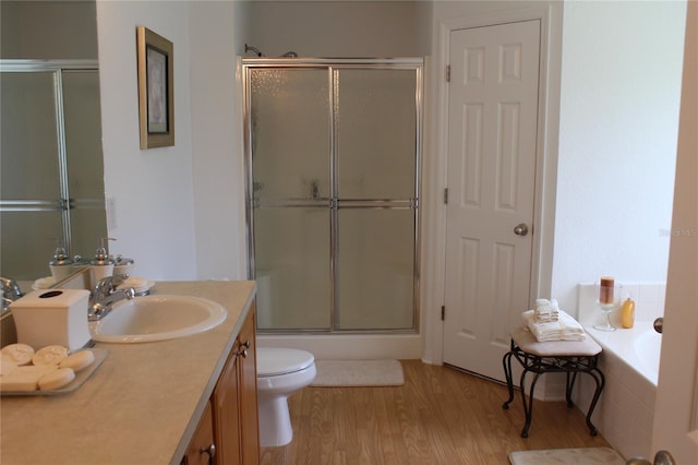 full bathroom featuring vanity, wood-type flooring, shower with separate bathtub, and toilet