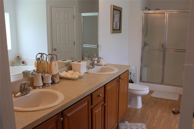 bathroom featuring wood-type flooring, vanity, toilet, and a shower with door