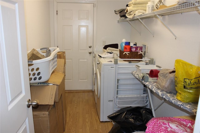 clothes washing area with washing machine and dryer and light hardwood / wood-style flooring