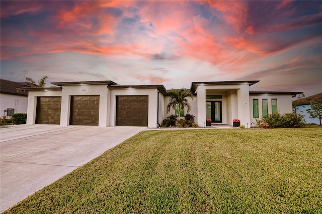 view of front of home with french doors, a garage, and a lawn