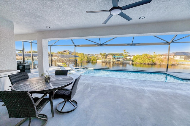 exterior space with glass enclosure, ceiling fan, a patio area, and a water view