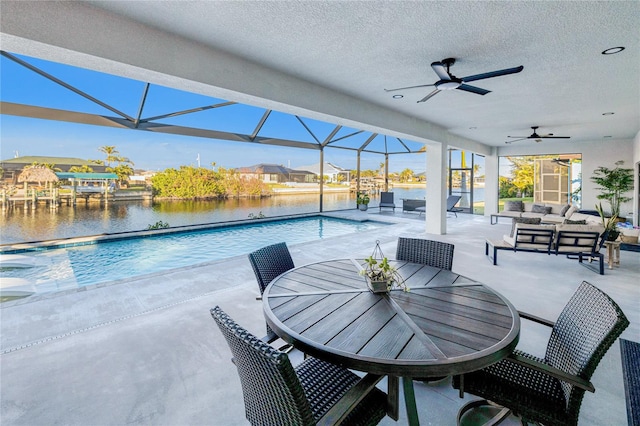 view of patio featuring a lanai, an outdoor living space, ceiling fan, and a water view