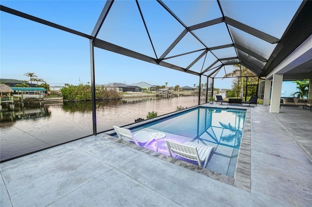 view of pool featuring glass enclosure, a water view, and a patio