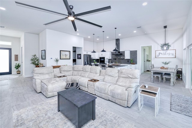 living room featuring ceiling fan, light wood-type flooring, and sink