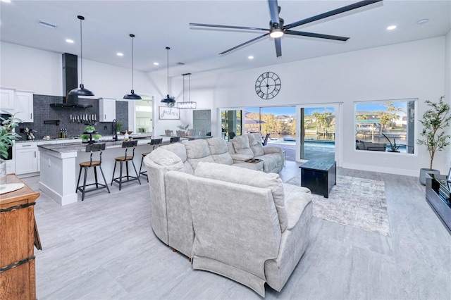 living room with a towering ceiling, ceiling fan, and sink