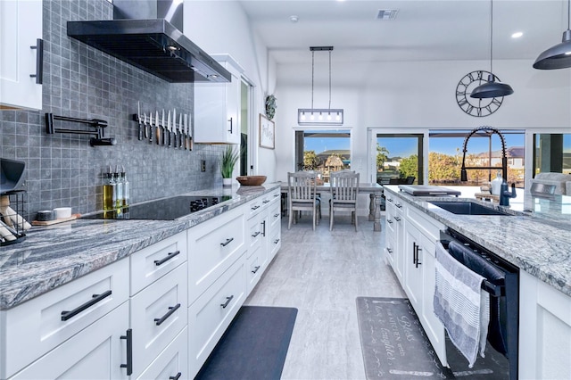 kitchen featuring white cabinetry, wall chimney exhaust hood, stainless steel dishwasher, decorative light fixtures, and black electric cooktop