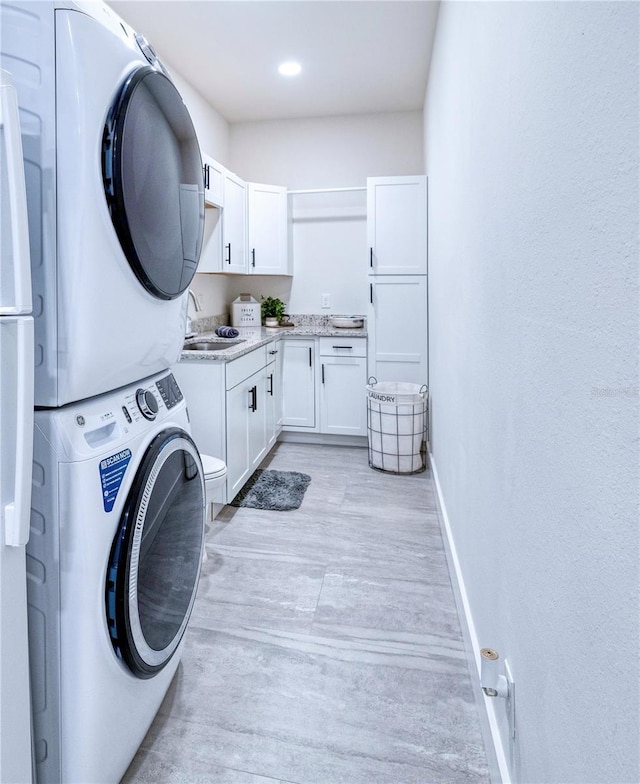 washroom with light hardwood / wood-style flooring, cabinets, sink, and stacked washer and clothes dryer