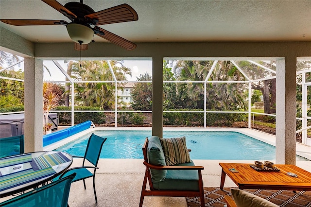 view of pool with a patio, glass enclosure, and ceiling fan