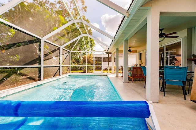 view of swimming pool featuring a patio area, ceiling fan, and glass enclosure