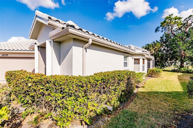 view of side of property featuring a garage and a yard