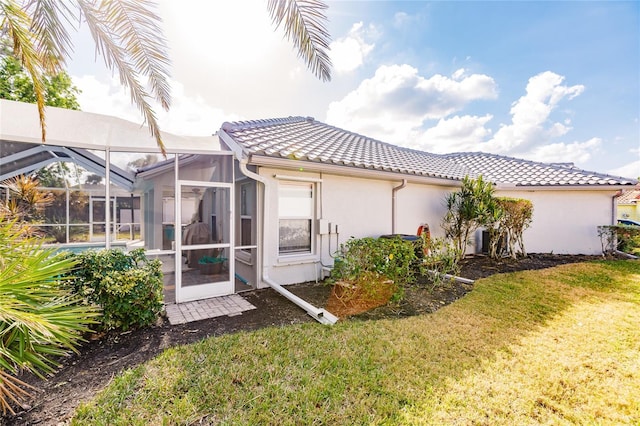 back of property featuring a lanai and a yard