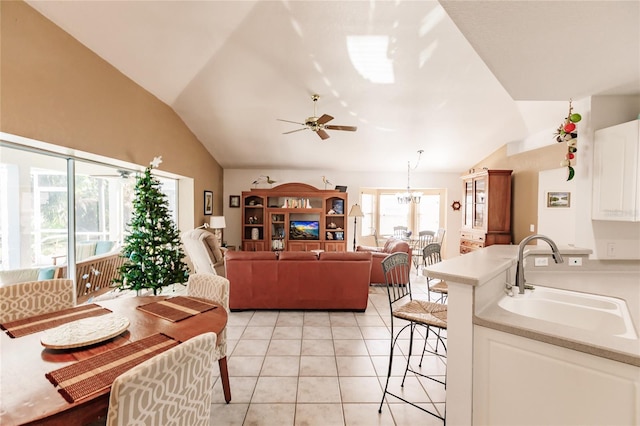 interior space with ceiling fan with notable chandelier, light tile patterned floors, sink, and vaulted ceiling