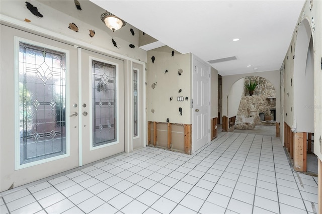 tiled spare room featuring a fireplace and french doors