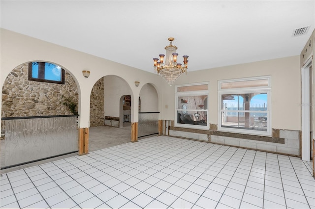 empty room featuring a chandelier and light tile patterned floors