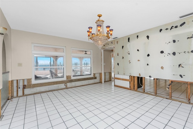 empty room with light tile patterned floors and a chandelier