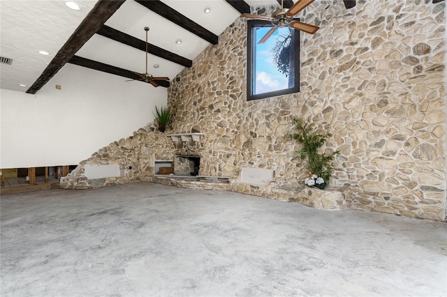 unfurnished living room with concrete flooring, ceiling fan, high vaulted ceiling, beamed ceiling, and a stone fireplace