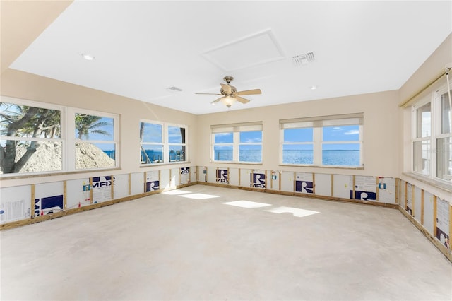 unfurnished living room featuring ceiling fan, plenty of natural light, and a water view