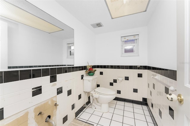 bathroom featuring tile patterned flooring, toilet, and tile walls