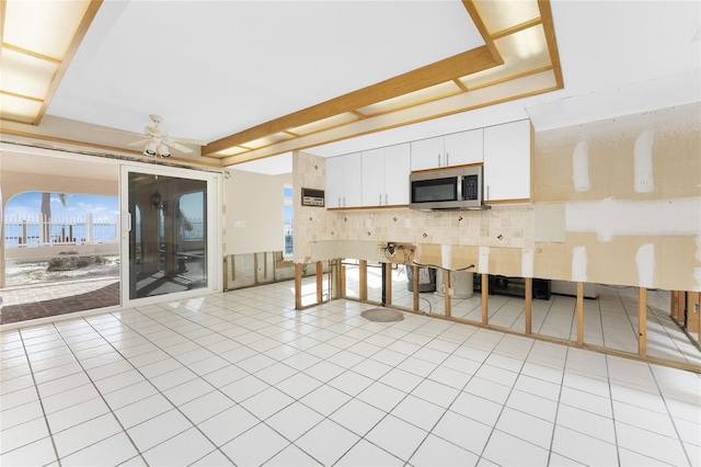 kitchen with white cabinets, light tile patterned floors, tasteful backsplash, and ceiling fan