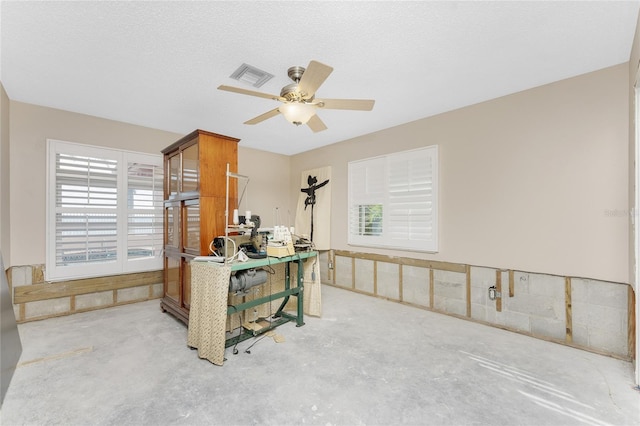 home office featuring concrete flooring, ceiling fan, and a textured ceiling