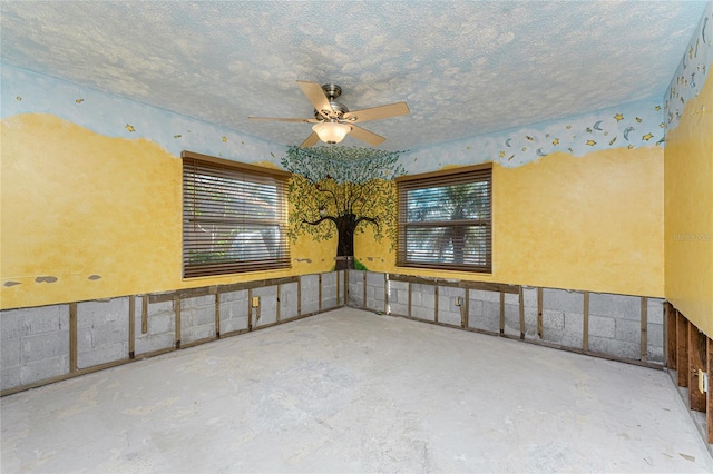 unfurnished room with ceiling fan, a textured ceiling, and concrete floors