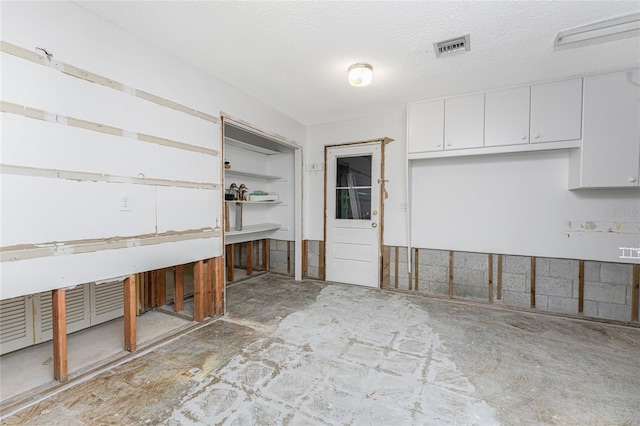 kitchen with a textured ceiling and white cabinetry