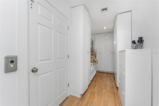 hallway with a textured ceiling and light hardwood / wood-style flooring