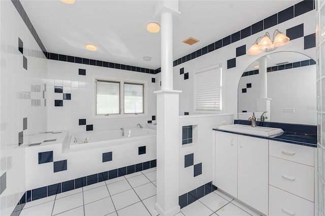 bathroom with tiled bath, tile walls, tile patterned flooring, and vanity