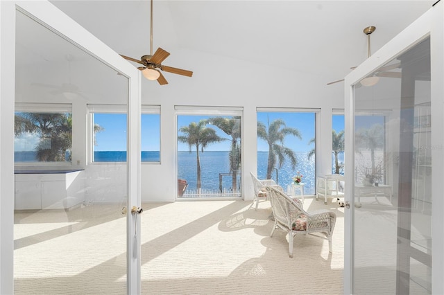 sunroom / solarium with ceiling fan, a water view, and french doors