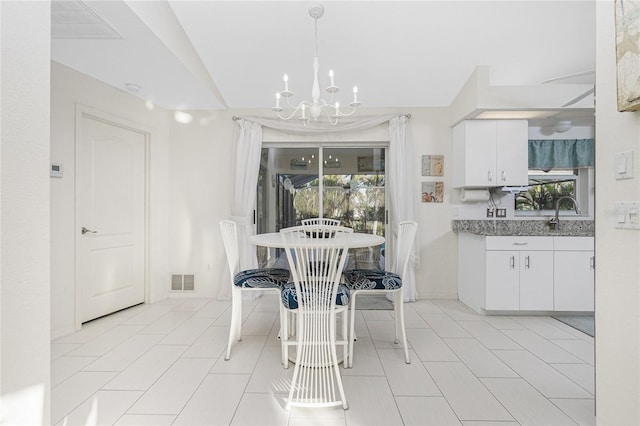 tiled dining space featuring sink, plenty of natural light, and an inviting chandelier