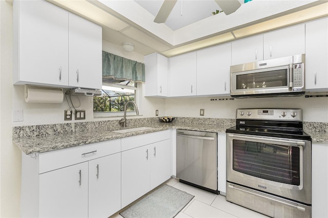 kitchen with white cabinets, sink, light tile patterned floors, appliances with stainless steel finishes, and light stone counters