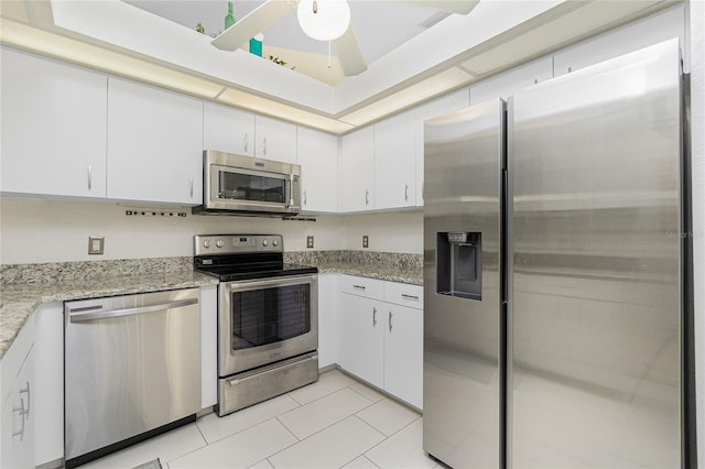 kitchen featuring white cabinets, light stone counters, light tile patterned floors, and stainless steel appliances