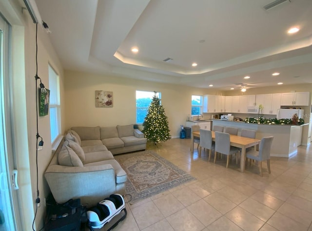 tiled living room featuring a tray ceiling, ceiling fan, and sink